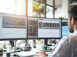 Man analyzing stock market data on multiple screens